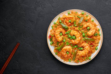 Taylandlı Tom Yum Fried Rice veya Biryani beyaz tabakta siyah arka planda. Tom Yum Fried Rice yasemin pilavı, karides ve sebzeli Tayland mutfağıdır. Tayland yemeği. Uzayı kopyala Üst görünüm