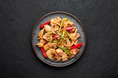 Tayland Ginger tavuğu ya da siyah arkaplanda siyah tabakta Gai Pad King. Gai Pad King, Tayland mutfağında tavuk eti, zencefil şeritleri, soğan, kapsiyum ve sosla servis edilir. Tayland Yemeği.