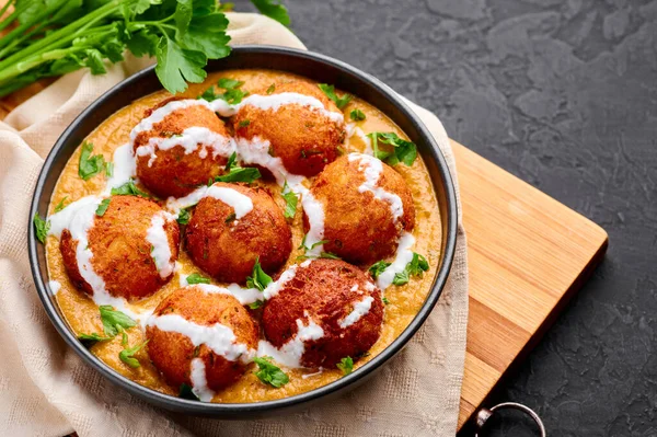 Malai Kofta Curry siyah kasede, arka planda. Malai Kofta, Hint mutfağı. Patates ve paneer peynirli. Soğan soslu kızarmış toplar. Hint Yemeği.