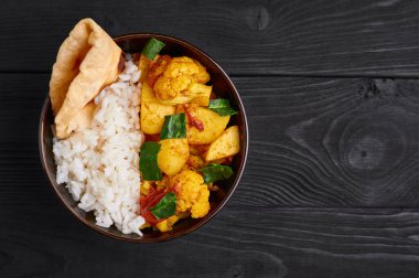 Pilav ve soslu aloo gobi. Hint mutfağı vejetaryen yemeği karnabahar, patates, zencefil, sarımsak ve baharatla pişirilir. Kimyon, kişniş, acı biber ve garam masala. Siyah tahta arkaplan