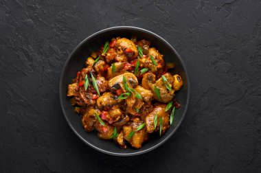 Mançurya mantarı siyah kasede, siyah arka planda. Mançurya mantarı - Hint Çin mutfağında bol yağda kızartılmış mantar, dolmalık biber, sos ve soğan.