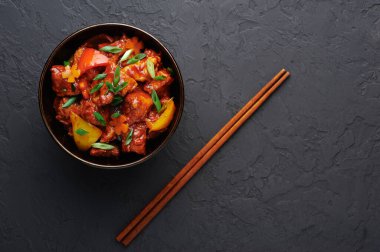 Siyah beton arka planda kasede Mançurya usulü tavuk. Mançurya usulü tavuk göğsü, dolmalık biber, domates ve soya soslu Hint yemeği. Boşluğu kopyala