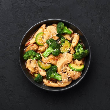 Hunan Chicken siyah kasede, arka planda. Hunan Chicken Çin mutfağı ya da Çin mutfağı brokoli, kabak, shiitake mantarı ve hunan sosuyla servis edilir. en üstteki görünüm