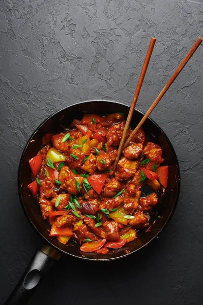 Siyah beton arka planda tavuklu mançurya. Mançurya usulü tavuk göğsü, dolmalık biber, domates ve soya soslu Hint yemeği. Boşluğu kopyala