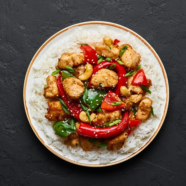 Siyah arkaplanda basmati pilavlı Schezwan Tavuğu veya Ejderha Tavuğu. Szechuan tavuğu popüler Hint-Çin baharatlı baharatlı biber, tavuk ve sebzedir..