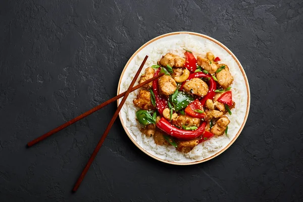 Siyah arkaplanda basmati pilavlı Schezwan Tavuğu veya Ejderha Tavuğu. Szechuan tavuğu popüler Hint-Çin baharatlı baharatlı biber, tavuk ve sebzedir..