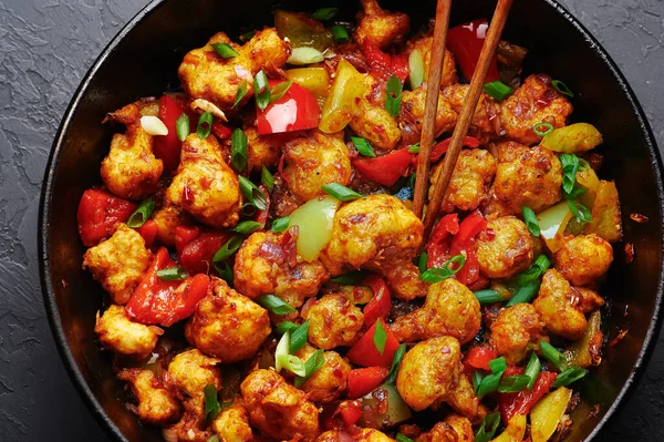 Gobi Mançuryalı siyah beton arka planda. Gobi Mançurya Hint mutfağı içinde karnabahar, domates, soğan ve soya sosu var..