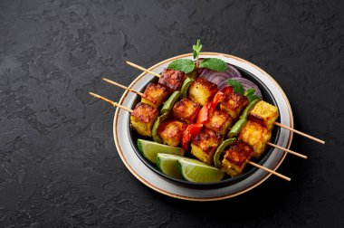 Paneer Tikka, siyah kasenin içinde, arka planda. Paneer tikka, içinde sebze ve baharat bulunan ızgara paneer peyniri olan bir Hint mutfağı. Hint yemeği. Boşluğu kopyala