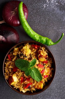 Siyah arka planda vejetaryen paneer biryani. Paneer biryani, paneer peyniri, basmati pilavı, masala, acı biber ve naneli geleneksel Hint mutfağıdır. Uzayı kopyala Dikey