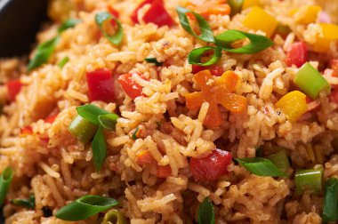 Sebze Schezwan kızarmış pilavı siyah kasede, arka planda. Vejetaryen Szechuan pirinci, Çin mutfağında dolmalık biber, yeşil fasulye ve havuç ile yapılan bir yemektir. Kapat.