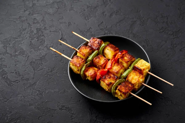 Paneer Tikka, siyah kasenin içinde, arka planda. Paneer tikka, içinde sebze ve baharat bulunan ızgara paneer peyniri olan bir Hint mutfağı. Hint yemeği. Boşluğu kopyala