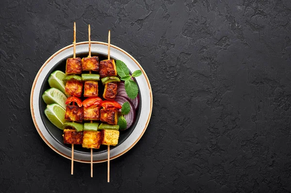 Paneer Tikka, siyah kasenin içinde, arka planda. Paneer tikka, içinde sebze ve baharat bulunan ızgara paneer peyniri olan bir Hint mutfağı. Hint yemeği. Üst Manzara. Boşluğu kopyala
