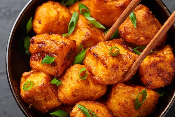 Paneer Mançurya ya da Paneer 65, siyah beton arka planda kasede. Paneer Mançurya, Çin mutfağında panner peyniri, domates, soğan ve soya sosu ile servis edilir. Kapat.