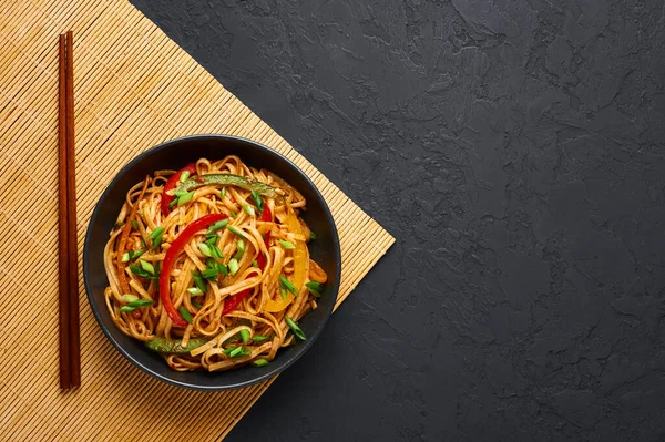 Vejetaryen Schezwan Eriştesi ya da Sebze Hakka Eriştesi ya da siyah arka planda Chow Mein. Hint-Çin mutfağı, udon eriştesi, sebze ve biber soslu sıcak yemek. Boşluğu kopyala