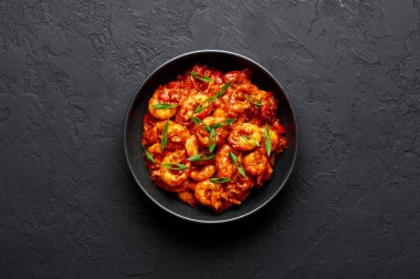 Schezwan Karidesleri siyah kasede, arka planda. Schezwan Karidesleri, Schezwan Sosu 'nda kızartılmış karides ve karidesli Hint-Çin mutfağı köri yemeği..