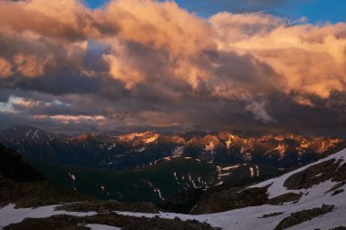 Dağların manzarasında göz kamaştırıcı bir gün batımı. Bulutlu gökyüzü ile dağ sıralı günbatımı manzarası. Cheget-Chat Range ve Chigordali Range, Karachay-Cherkerssia 'daki Kafkas Dağları, Rusya.
