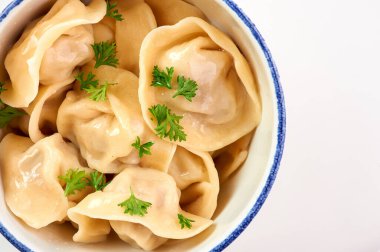 Beyaz ahşap masada maydanozlu ve soğanlı hamur tatlısı. Pelmeni - içinde kıyma olan geleneksel Rus yemek hamuru. Kopyalama alanı ile yakın çekim