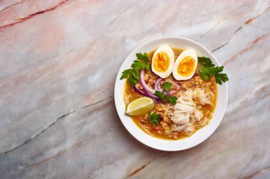 Mohinga mermer arka planda. Mohinga, kedibalıklı, pilav erişteli, tavuk yumurtalı ve limonlu bir burma balık çorbası. Uzayı sola kopyala