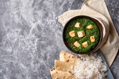 Palak Paneer şapkası ve gri beton arka planda basmati pirinci. Palak paneer ya da yeşil paneer, ıspanak ve paneer peynirinin Hint mutfağından yapılan bir yemektir. Boşluğu kopyala