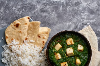 Palak Paneer şapkası ve gri beton arka planda basmati pirinci. Palak paneer ya da yeşil paneer, ıspanak ve paneer peynirinin Hint mutfağından yapılan bir yemektir. Boşluğu kopyala
