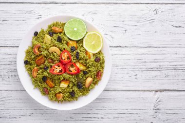 Beyaz ahşap arka planda Palak Paneer Biryani. Palak Paneer Biryani, ıspanaklı, paneer peynirli, basmati pilavlı, baharatlı, fındıklı ve kuru üzümlü vejetaryen Hint mutfağı. Üst Manzara. Boşluğu Kopyala