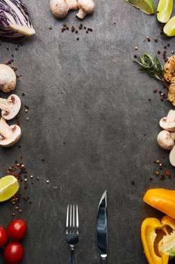 food background. raw vegetable ingredients with cutlery around grey stone background. free space for text. Frame of organic food.