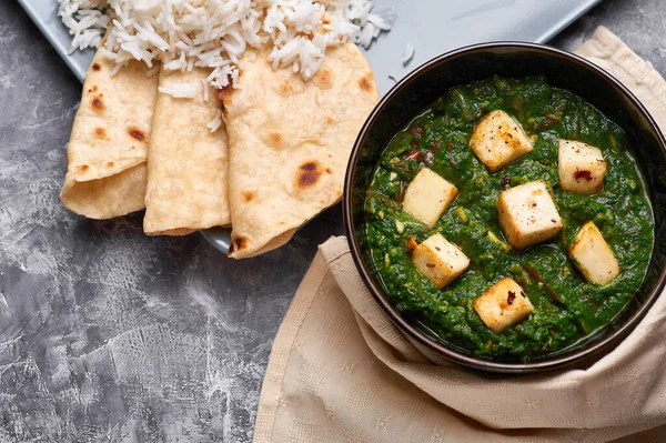 Palak Paneer şapkası ve gri beton arka planda basmati pirinci. Palak paneer ya da yeşil paneer, ıspanak ve paneer peynirinin Hint mutfağından yapılan bir yemektir. Boşluğu kopyala