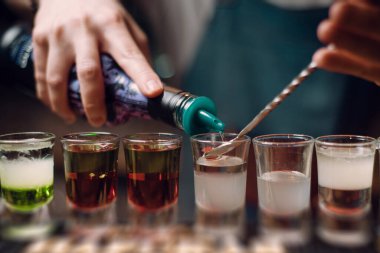 barman pouring shots at a bar counter. barman hands work close up. copy space