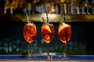 three aperol spritz cocktail decorated with rosemary at bar counter. copy space