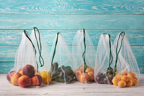 Fruits and vegetables in reusable eco bags at blue wooden background. Recycled bags instead of plastic bags. Plastic free.