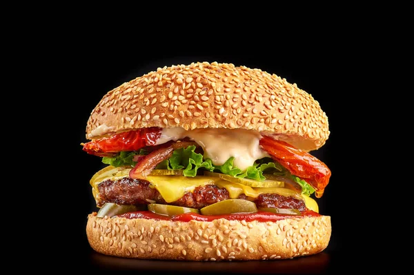 burger at black background with beef or pork cutlet or steak with fried tomatoes, cheddar cheese, pickled cucumber, lettuce and ketchup in white bun with sesame