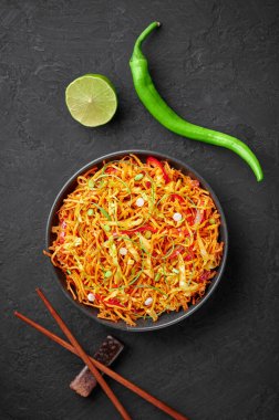 Siyah kasedeki Çin Bhel 'i siyah tahta masa üstünde. Çin Bhel Hint-Çin mutfağı sokak yemekleri, kızarmış hakka eriştesi, sebze ve şempanze sosu.