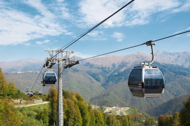 Dağ manzarasında gri kabinleri olan teleferik yolu. Sonbahar. Sochi, Rosa Khutor.