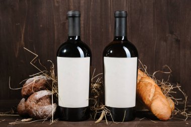 Ekmek, iki şişe şarap ve kahverengi ahşap arka planda şarap karışımı.