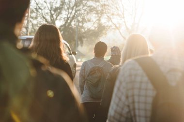 Gün ışığında yolda yürüyen bir grup insanın fotoğrafı var. Arka görüntüyü kapatın. Fotoğraf Munnar, Hindistan 'da çekildi.