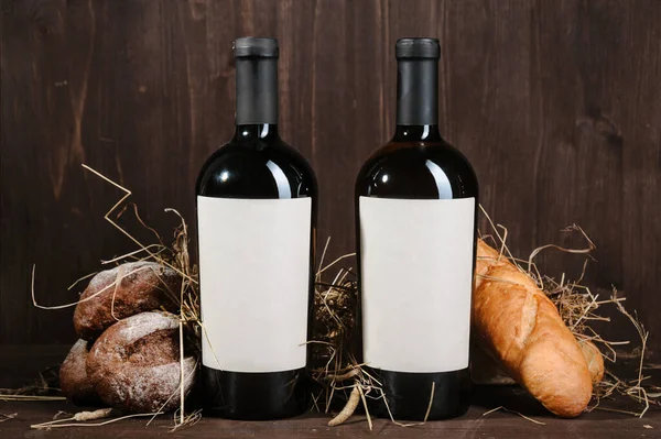 Ekmek, iki şişe şarap ve kahverengi ahşap arka planda şarap karışımı.