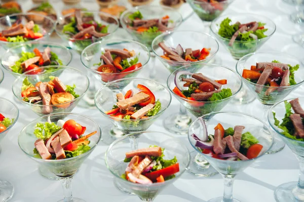 wine glasses with salad and meat snack at reception. catering snack