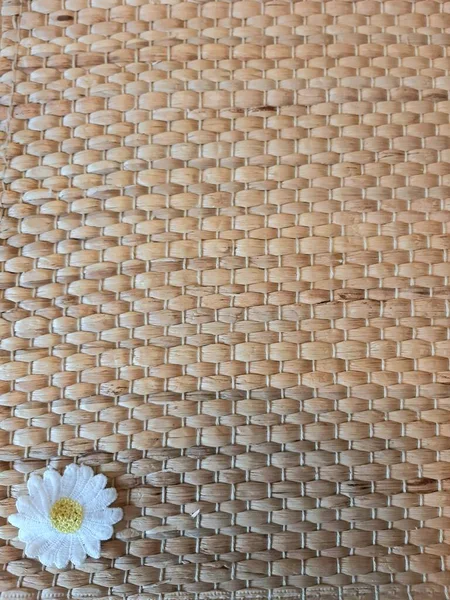 Hasır bir halıya örülmüş papatya.