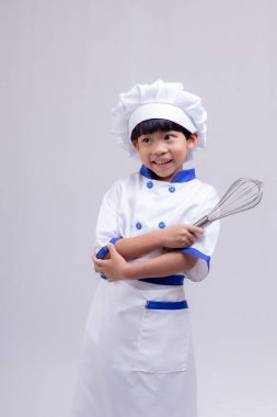Beyaz arka planda şef üniforması giyen sevimli çocuk.