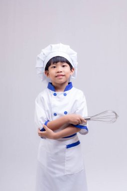 Beyaz arka planda şef üniforması giyen sevimli çocuk.