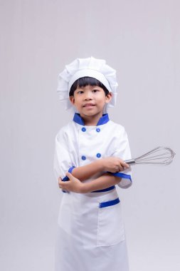 Beyaz arka planda şef üniforması giyen sevimli çocuk.