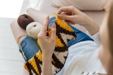 a woman knitting warm socks at home clipart