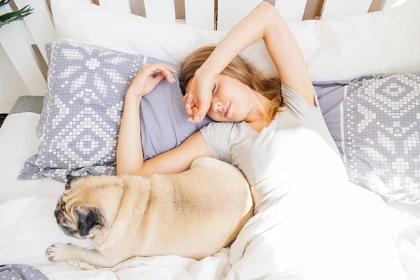 Mujer joven con su perro en una cama. Desayuno en la cama — Foto de Stock