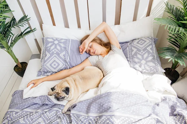 Ung kvinna med hennes hund i en säng. Frukost på sängen — Stockfoto
