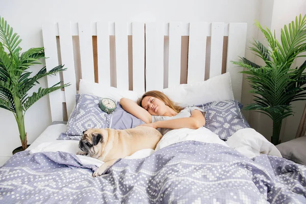 Ung kvinna med hennes hund i en säng. Frukost på sängen — Stockfoto