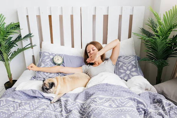 Ung kvinna med hennes hund i en säng. Frukost på sängen — Stockfoto