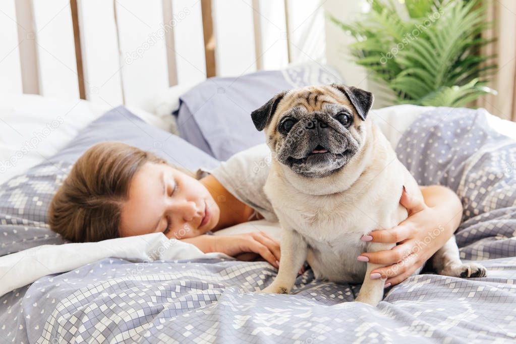 Young woman with her dog in a bed. Breakfast in bed