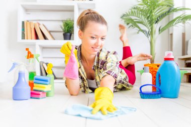 Koruyucu eldiven kadın gülümseyerek ve toz bir sprey ve bir toz bezi kullanarak silme