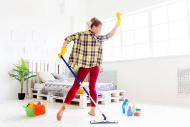 Koruyucu eldiven kadın gülümseyerek ve toz bir sprey ve bir toz bezi kullanarak silme