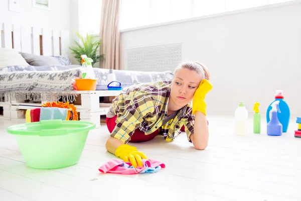 La mujer con guantes protectores sonríe y limpia el polvo con un aerosol y un plumero — Foto de Stock